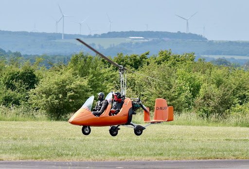 Tragschrauber beim Abheben über der Wiese